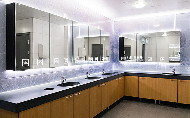 Novosan Pala-peilikaapit kauppakeskus Lanternan asiakas-WC:ssä. Vessassa on neljä käsienpesupaikkaa, hanat ja valaistut Novosan peilikaapit. Vessan seinien pintakuviointi on rosoinen ja sinisen sävyinen. Allastasot ovat mustat ja kaappien ovet ruskeat.