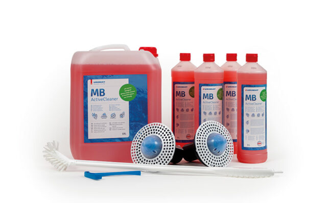 Kuvassa nestemäiset Mb-activeCleaner -pesuaineet, 10 litran kanisteri ja 4 kappaletta 1 litran pesuainepulloja. Pesuaineiden lisäksi kuvassa Mb-ActiveTrap -hajulukot ja pitkävartinen pisuaariharja.