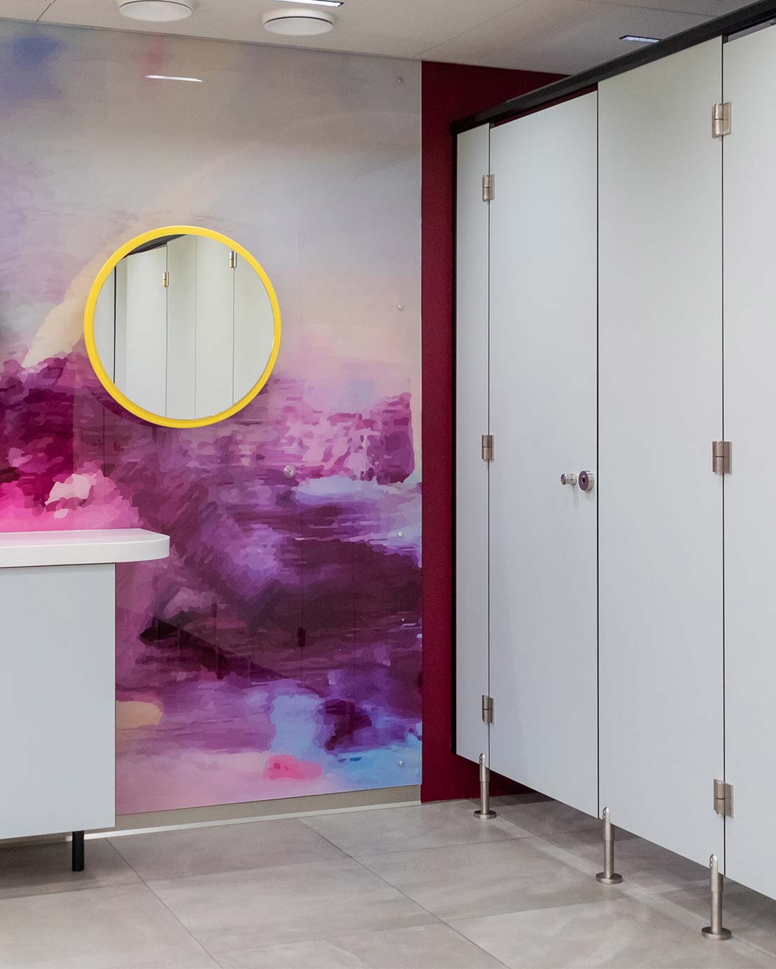 Novosan, WC-koppi, jakoseinä, malliltaan Classic ja sävyltään vaaleansininen. WC-tilassa on useita eriöitä, joiden ovet ovat kiinni. Eriöiden helat on valmistettu ruostumattomasta teräksestä. Katto on valaistu ja laattalattia on vaaleanharmaa. WC-koppien viereisellä seinällä on pyöreä seinäpeili ja vaaleansininen apupöytä. Pöytätaso on valkoinen.