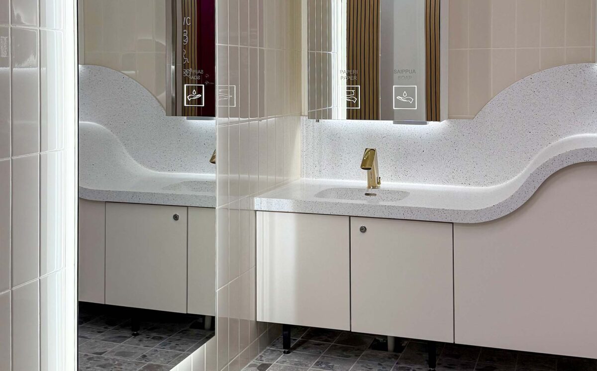 Kauppakeskus Revontulen uudet WC-tilat, joissa on kullan sävyinen hana, kaareva allastaso ja valaistu peilikaappi.