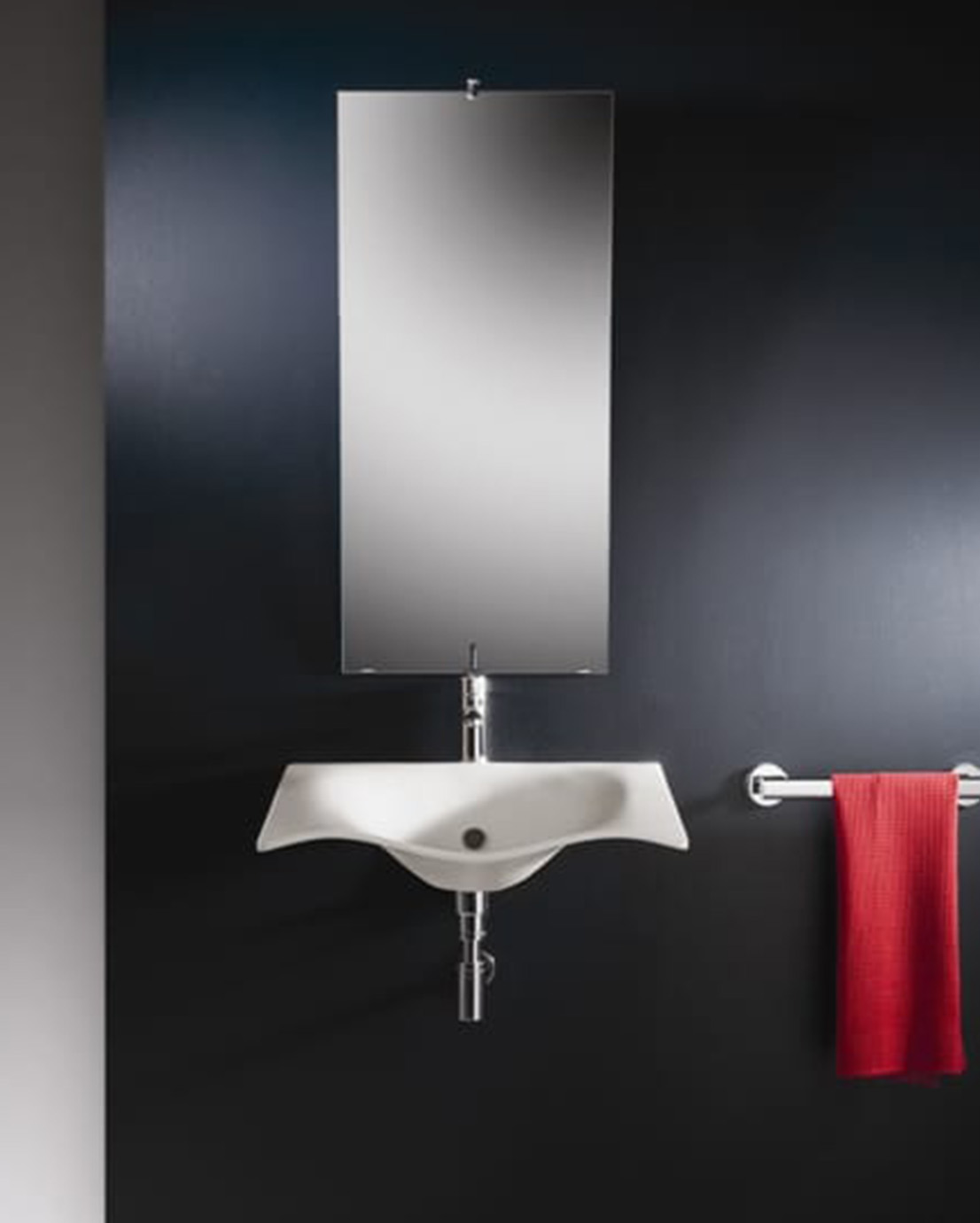 Kuvassa esteetön Novosan Pito aalto -pesuallas tummanharmaalla WC:n seinällä. Pesualtaan päällä peili ja sivulla pyyhetanko.